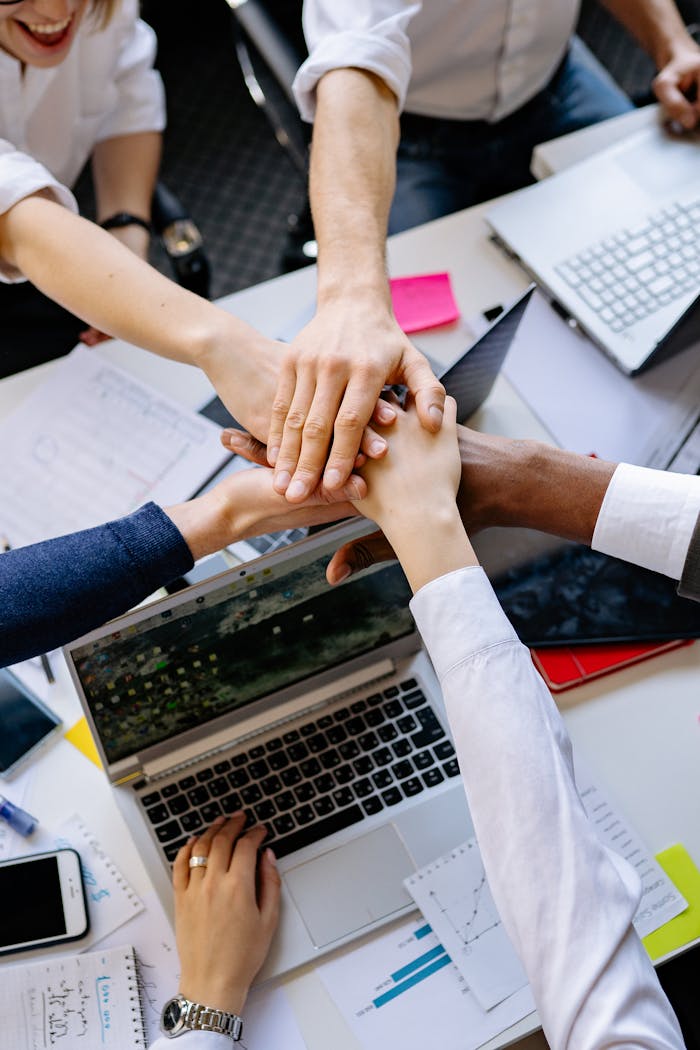 A diverse group of professionals stacking hands over a table symbolizing teamwork and collaboration.
