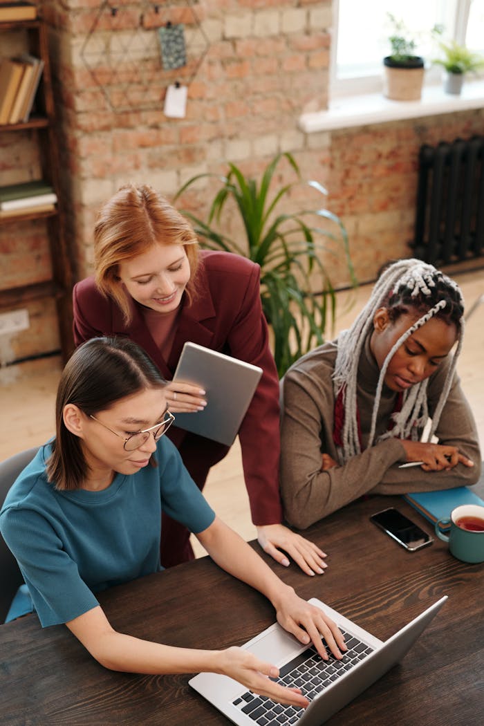 Three women working together in a modern office setting, showcasing teamwork and diversity.